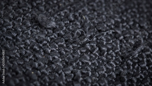 Close-up macro shot of dark black textured fabric with loose threads and pilling