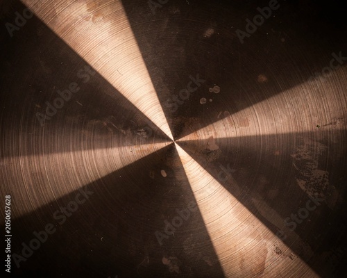 Close-up of brushed metal surface with dramatic radial light and shadow patterns