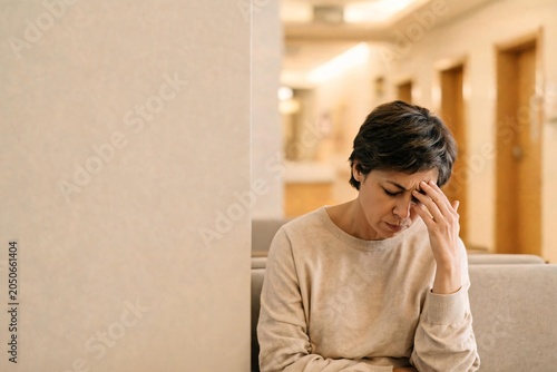 Woman suffering headache or stress in hospital waiting room