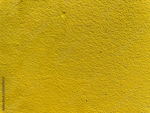 Landscape close up full frame view of a rough granular textured surface covered in solid vibrant bright yellow paint