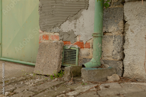 Canvas Print Close-up view of a weathered building base showing a chipped plaster and brick w