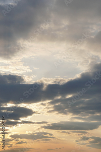 Scenic sky background with dark clouds and golden sunlight breaking through. Beautiful dramatic cloudy landscape during sunset, peaceful nature 