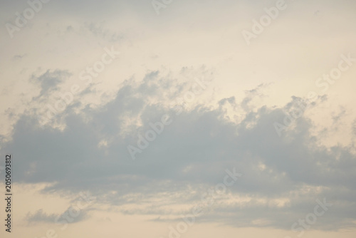Soft grey clouds floating in a pale pastel evening sky. Minimalist cloudscape during sunset, serene and peaceful nature