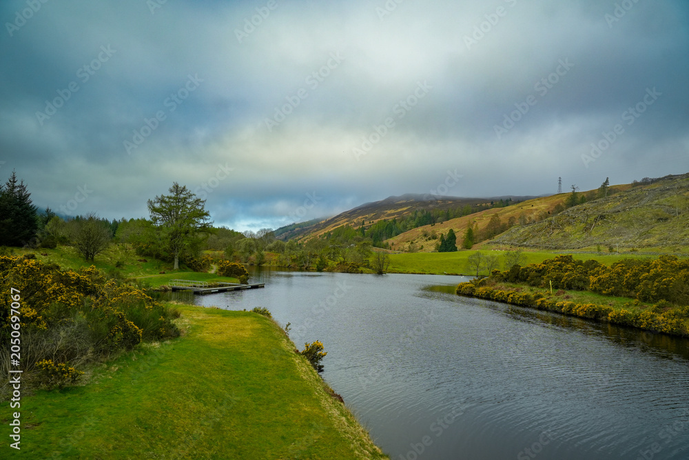 Fototapeta premium A wide, calm stretch of the Caledonian Canal—an artificial waterway in Scotland—with no locks. The Caledonian Canal is Scotland’s longest inland waterway