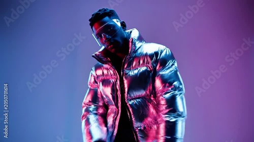 A muscular man in a shiny silver jacket flexing his arms against a colorful background