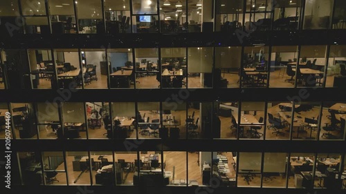 Offices at night with lights on and empty desks in the building