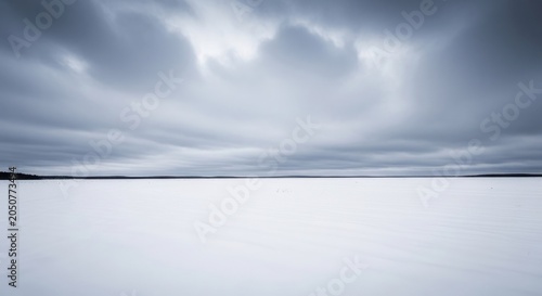 Vast snow field under dramatic grey clouds and horizon
