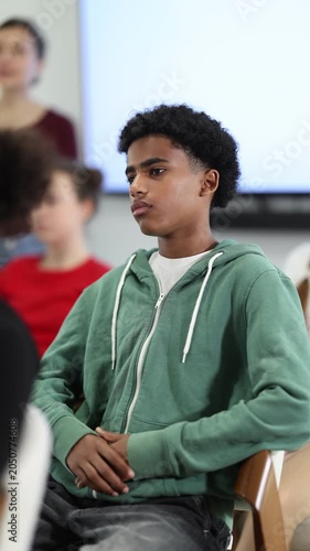 Attentive young male student focusing on lecture during interactive educational session in bright studio