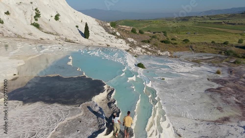 Discover the breathtaking beauty of Pamukkale in Turkey, where natural hot springs form stunning terraces. A couple strolls through the warm, turquoise waters surrounded by picturesque landscapes.