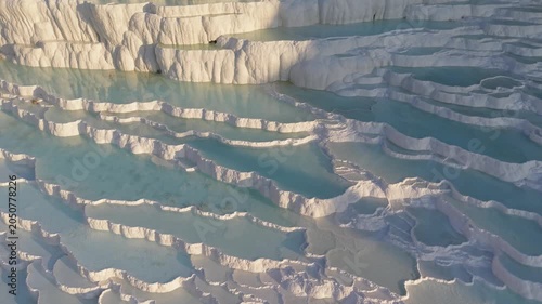 Pammukale Turkey mesmerizing travertine terraces shimmer under the soft light of dawn. Visitors walk along the mineral-rich pools and admire the natural beauty, creating unforgettable experiences.