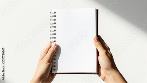 Hands holding open blank spiral notebook for notes