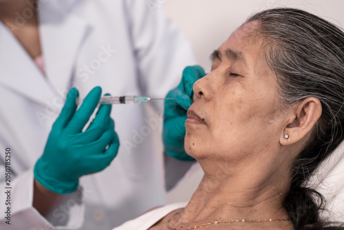 Принти на полотні Close up of a mature woman receiving a facial injection on her cheek during a co