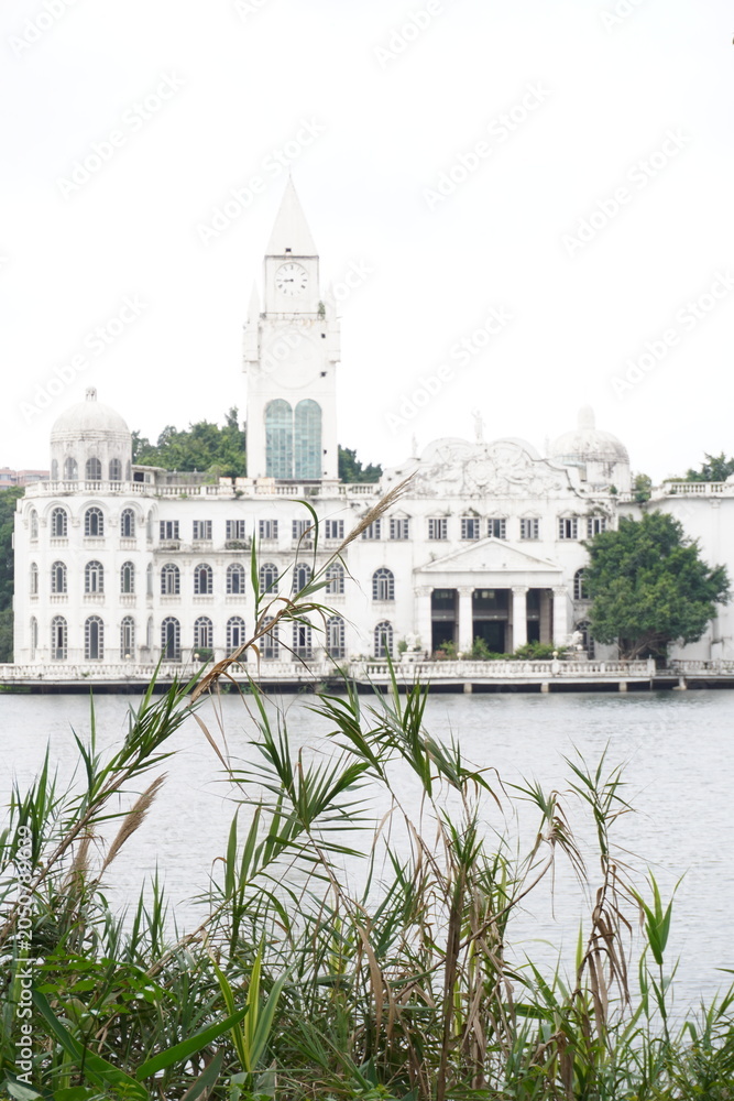 Fototapeta premium The white castle building opposite the grassland and the lake