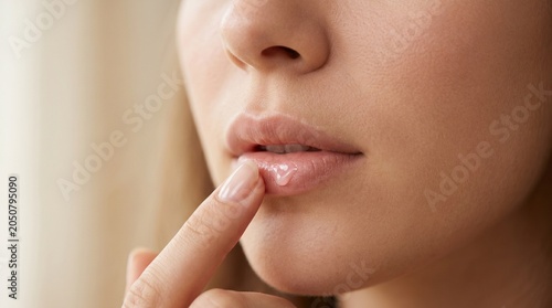 daily self-care, as a woman gently applies a nourishing, clear lip treatment to hydrate her lips.