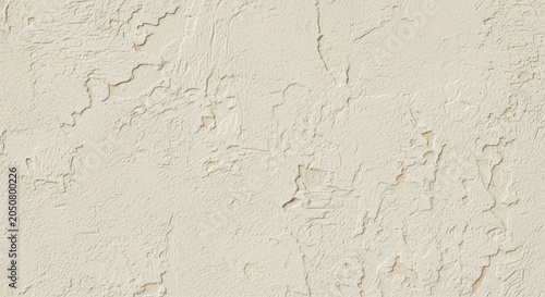 Closeup of a textured creamcolored wall with peeling paint