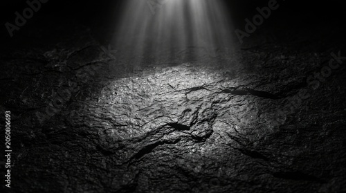 Dark rough stone surface illuminated by a beam of light shining down