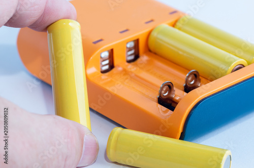 Obraz na plátně Close-up of a charger and batteries; a battery is being held in a hand