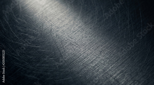 Scratched metal surface with a spotlight shining on it creating a gradient effect on the scratched metallic background