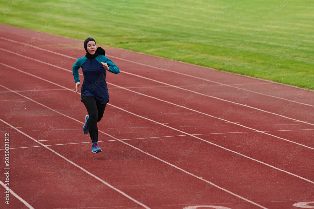 Fototapeta premium Female Athlete Running on Outdoor Track Wearing Sportswear and Headscarf During Training Session