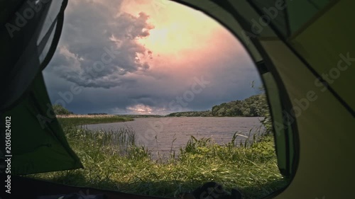 Dramatic stormy sky timelapse over river Kyiv region Ukraine. View from inside camping tent door. Fast moving dark thunderstorm clouds, rain approaching, strong wind blowing, waves on water.Adventure.