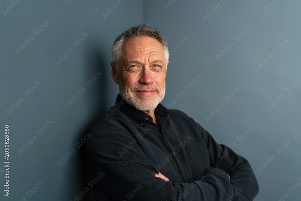 Obraz premium The man with folded arms posing confidently against a blue studio background