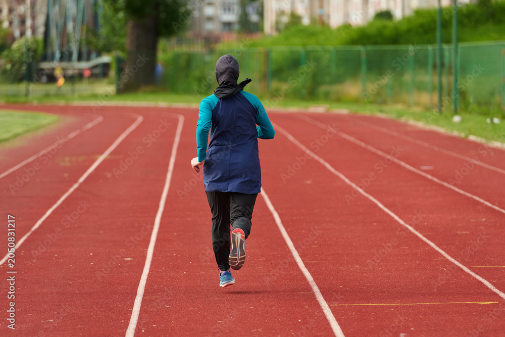 Fototapeta premium Woman Running on Outdoor Track in Headscarf Training for Fitness and Endurance