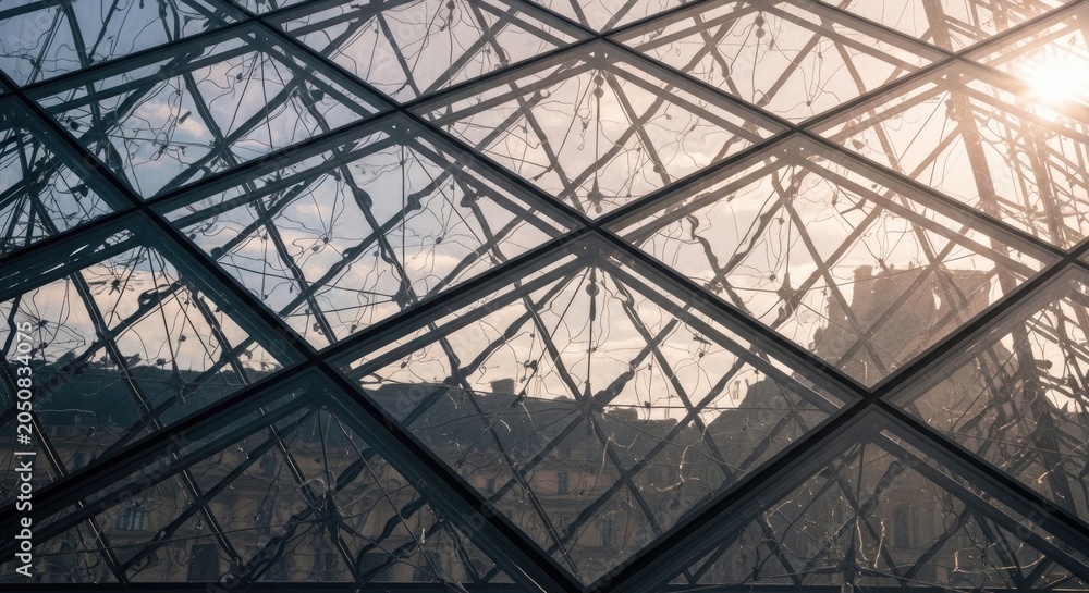 Fototapeta premium Architectural Marvel - Modern Glass Pyramid Structure with Sunlight and Sky.