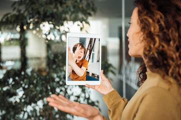 Businesswoman on video call talking to son at work place