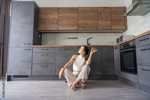 Tableau sur toile Young woman with apartment keys sitting inside furnished resale apartment kitchen