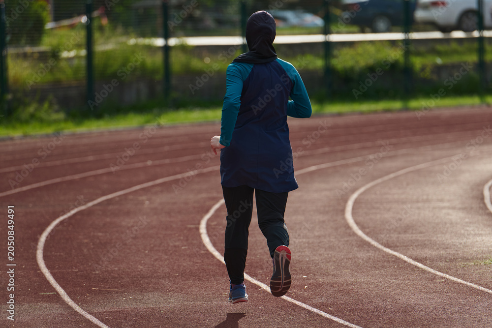 Fototapeta premium Woman in Hijab Running on Outdoor Track for Fitness Training and Active Lifestyle