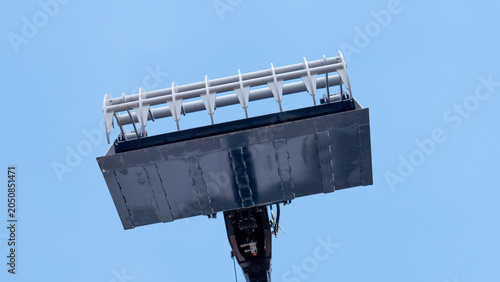 Fotografia Large metal construction attachment with tines and a dark underside, viewed from