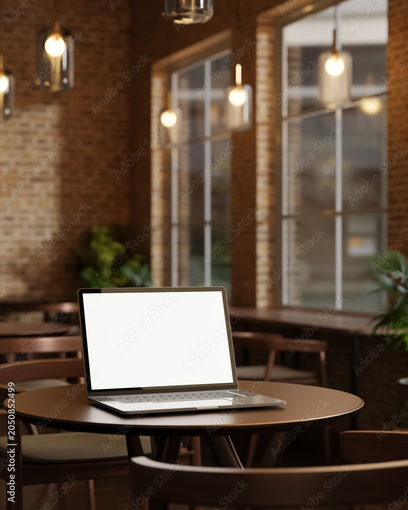 Fototapeta premium White screen laptop on round wooden table under glass lamp in bricks wall room at cafe or restaurant