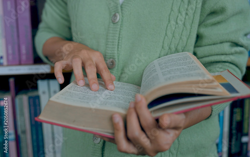 Close-up hand's woman reading book in library.