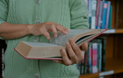 Close-up hand's woman reading book in library.