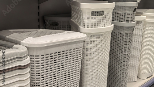 Schilderij op canvas White plastic rattan weave laundry hampers stacked on store shelf