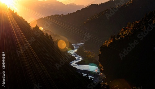 Sunlight streams over mountain valley, river winding