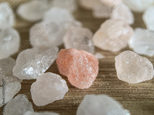 Foto Pink Himalayan salt crystal among white rock salt crystals on wooden surface