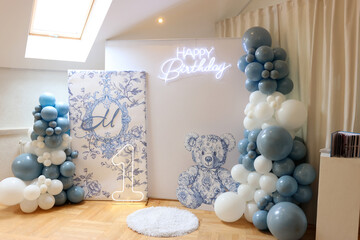 Festive first birthday photo zone with blue balloons and a decorative teddy bear for a boy.