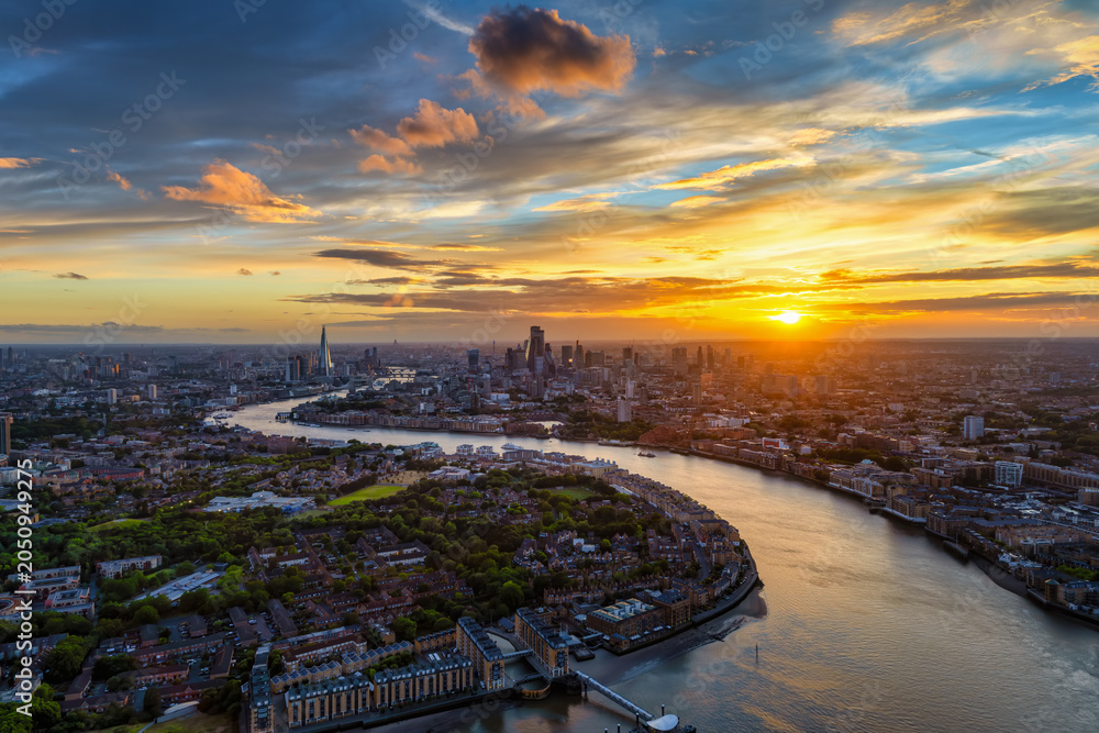 Obraz premium Wide panoramic sunset view of the London skyline in England with Thames River leading with its curved stream into the City