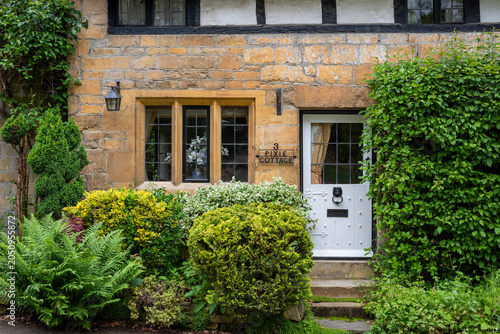 details of a facade of an old medieval house in Cotswolds, wooden white door and yellow window, oolitic stone