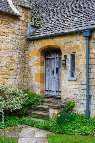 detail of an old medieval house in Cotswolds, oolitic yellow stone, wooden entrance door and window