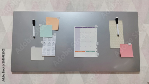 Magnetic board with calendar, paper note and marker. Office organizing tool for scheduling and planning tasks. Student study productivity concept with blank space for notes.