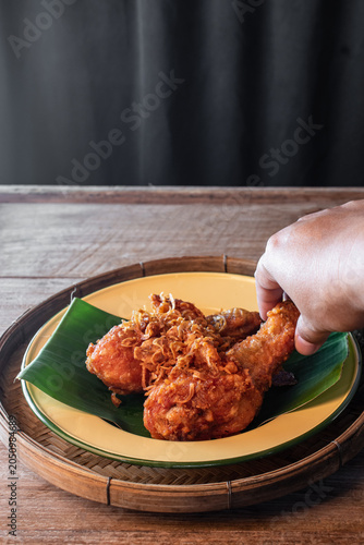 Obraz na płótnie Authentic Hat Yai fried chicken drumsticks topped with crispy fried shallots served on a green banana leaf in a wooden tray
