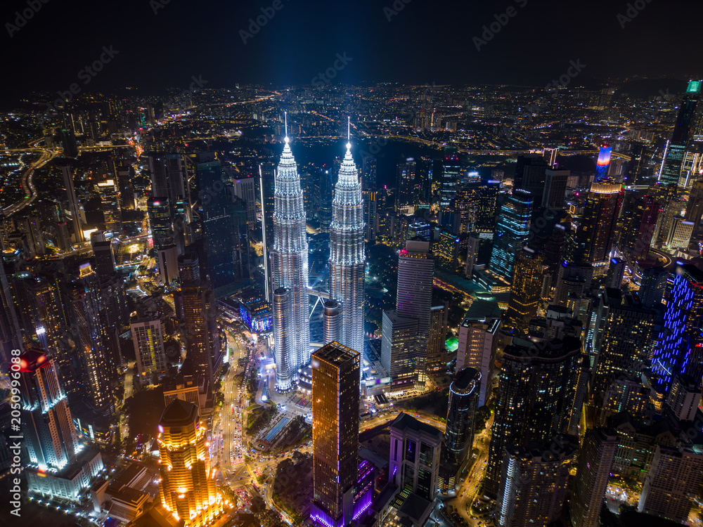 Fototapeta premium Aerial drone view of Kuala Lumpur downtown with illuminated skyscrapers and the city skyline at night, Malaysia.