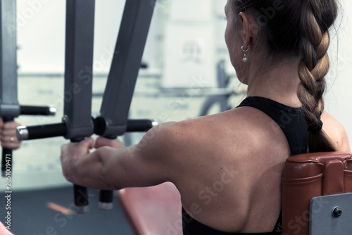 The trainer does exercises on various machines for the muscles of the arms, shoulders and back