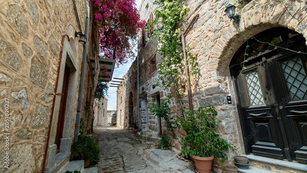 Fototapeta premium Chios, Greece - May 24, 2026: Scenic street view of Mesta village on Chios Island, Greece, featuring stone-built houses, narrow cobblestone streets, old walls, and the historic atmosphere