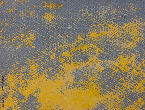 Принти на полотні Close-up of worn yellow paint over a patterned gray metal surface, creating an industrial grunge texture ideal for backgrounds, design projects, and urban themes