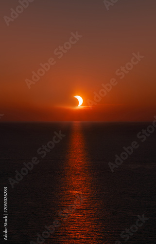 Partial solar eclipse at sunset over the ocean with the sun's reflection on the water of the Mediterranean near Menorca