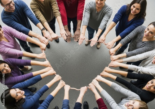 Diverse group of people joining hands in a circle around a heart shape isolated on white background