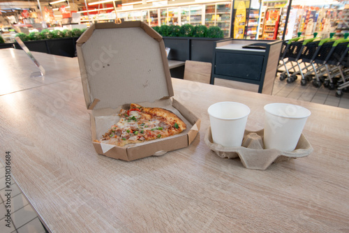 Pizza and drinks on a table in a grocery store food area during the day